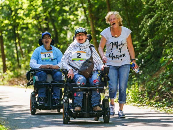 2 Frauen mit E-Rolli nehmen mit ihrer Begleitperson an einem Erlebnisrennen teil.