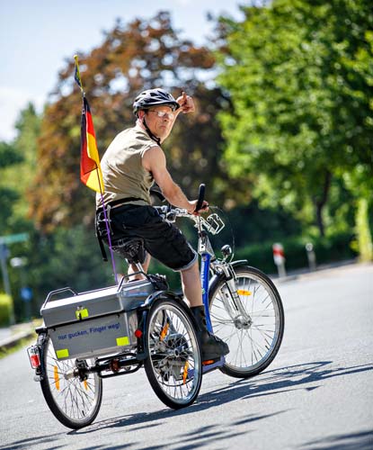 Ein Mann mit Beeinträchtigungen fährt auf seinem Fahrrad durch den Park.